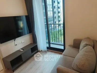 Modern living room with sleek TV setup and balcony view in urban apartment.
