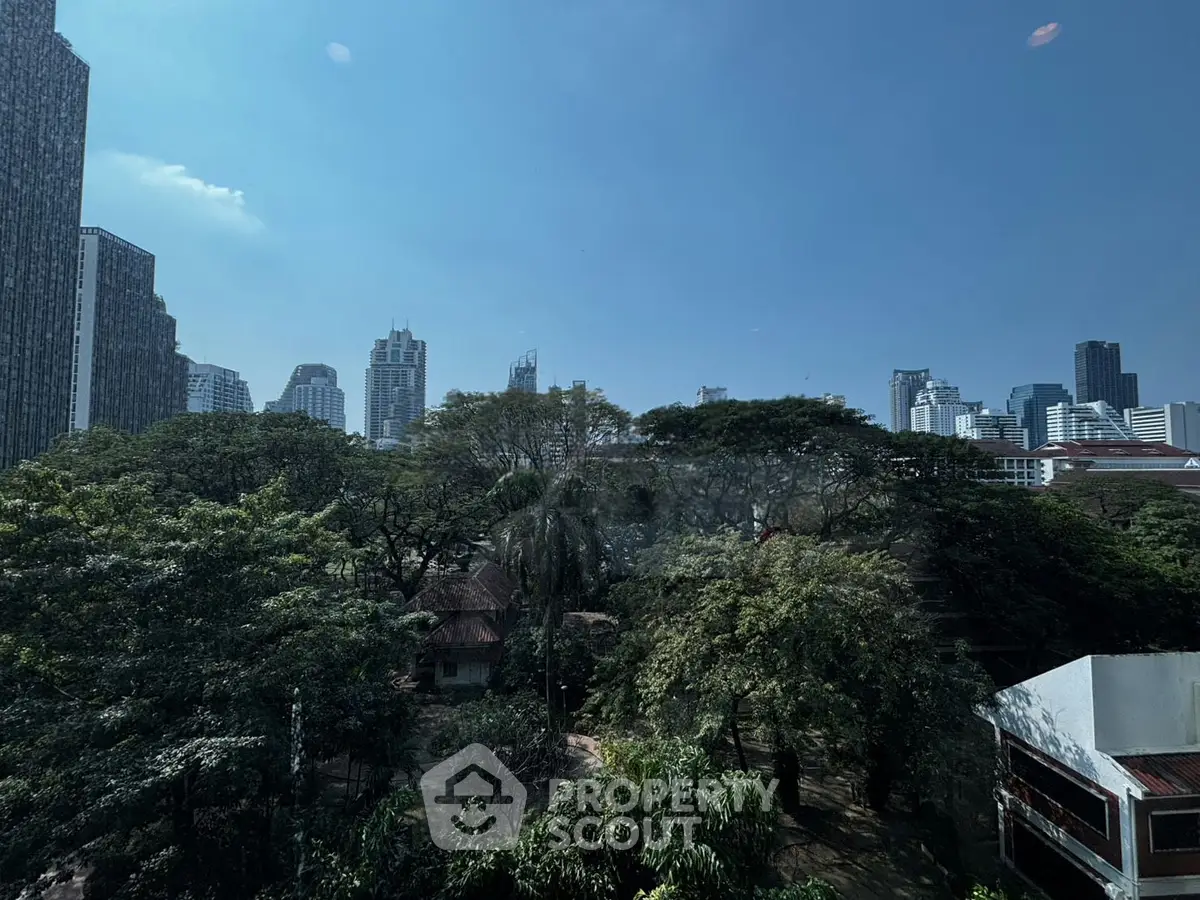 Stunning cityscape view with lush greenery and skyscrapers under a clear blue sky.