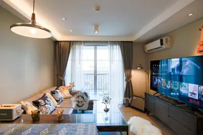 Modern living room with stylish decor, large TV, and balcony access, perfect for relaxation and entertainment.
