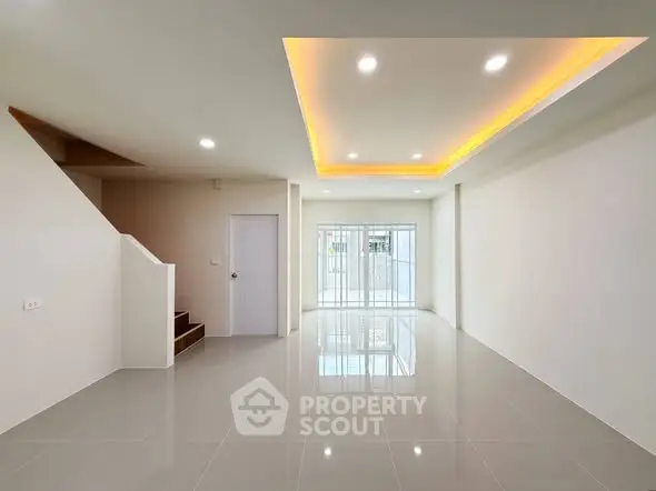 Spacious modern living room with sleek tile flooring and ambient ceiling lighting.