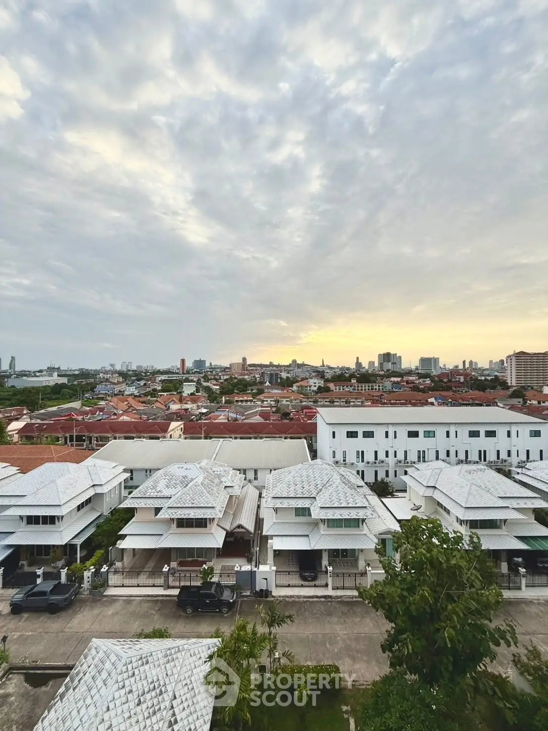 Stunning aerial view of residential neighborhood at sunset with city skyline in the background.