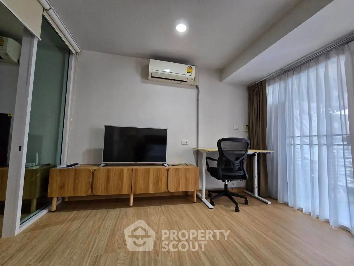 Modern living room with TV, air conditioning, and work desk in a bright apartment.