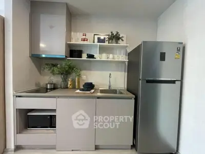 Modern kitchen with sleek cabinetry, stainless steel fridge, and open shelving for stylish storage.