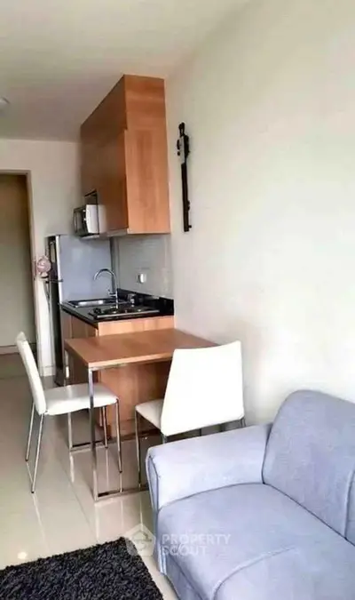 Cozy apartment with compact kitchen and dining area, featuring modern appliances and comfortable seating.