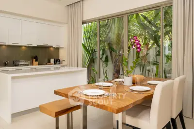 Modern kitchen with open layout and elegant dining area overlooking lush garden.