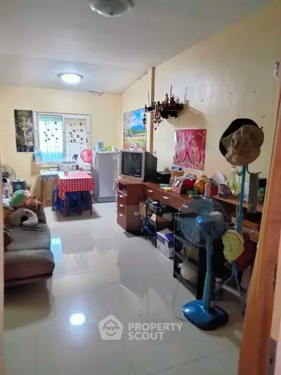 Cozy living room with tiled flooring, vintage TV, and eclectic decor in a compact apartment.