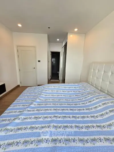 Spacious bedroom with modern decor and ample natural light, featuring a comfortable bed and stylish design.