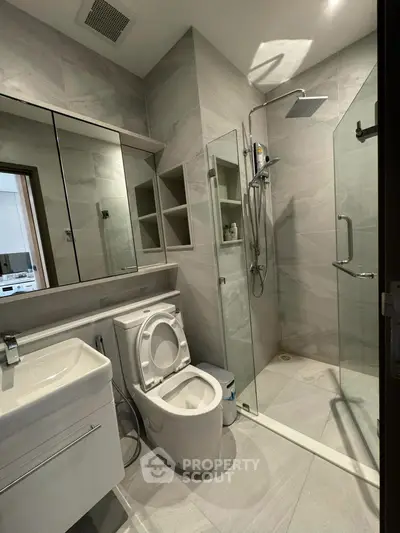 Modern bathroom with sleek design, featuring a glass shower enclosure and integrated storage solutions.