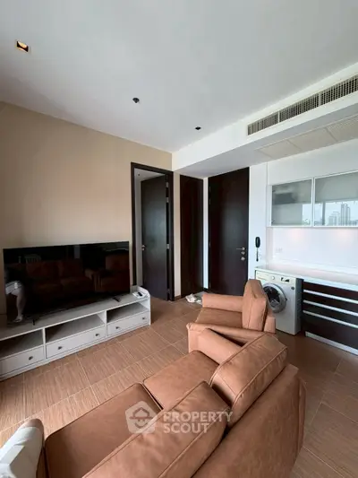 Modern living room with brown leather sofa, TV, and washing machine in a stylish apartment.
