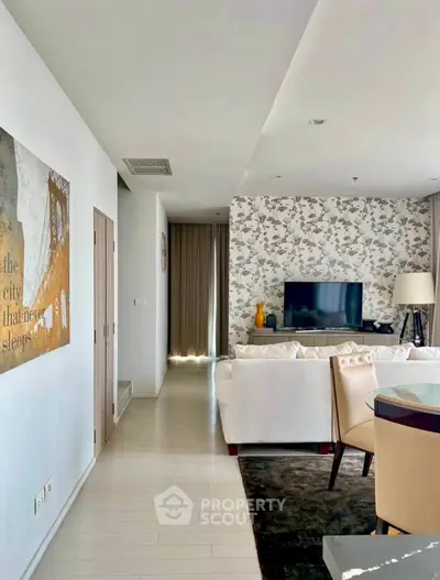 Stylish living room with modern decor and floral accent wall, featuring a cozy seating area and flat-screen TV.