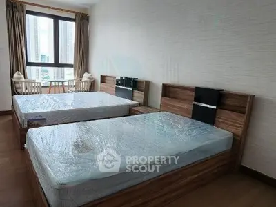 Spacious bedroom with twin beds and city view, perfect for urban living.