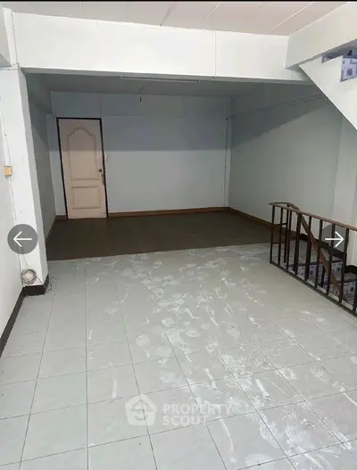 Spacious interior with tiled flooring and staircase, ideal for customization.