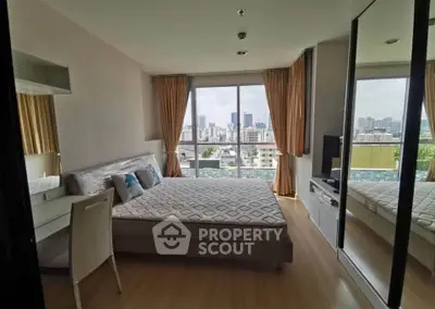 Spacious bedroom with city view, large windows, and modern furnishings in a high-rise apartment.
