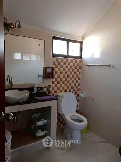 Modern bathroom with stylish sink and checkered tile accent wall.