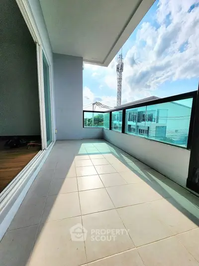 Spacious balcony with modern glass railing and scenic view, perfect for relaxation.