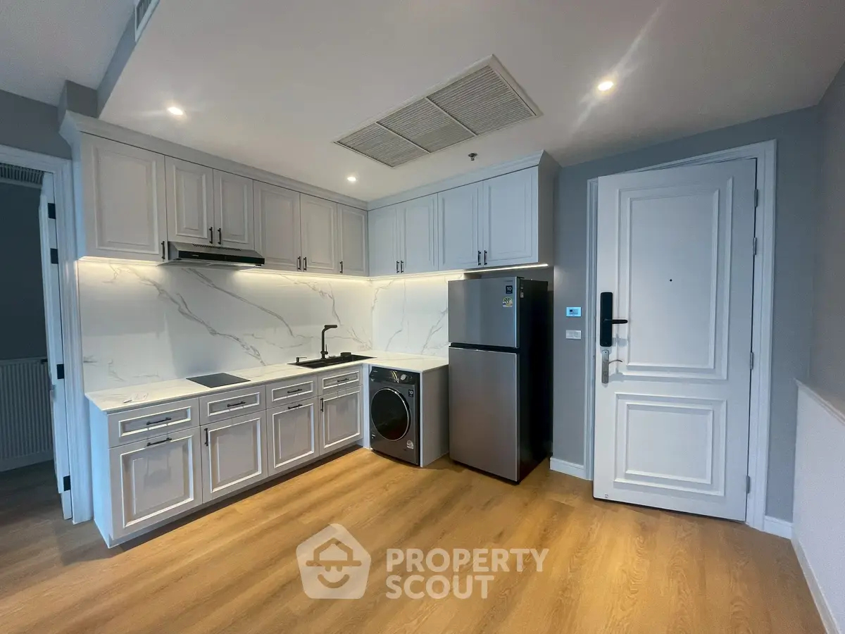 Modern kitchen with sleek cabinetry, integrated appliances, and elegant marble backsplash in a stylish apartment.