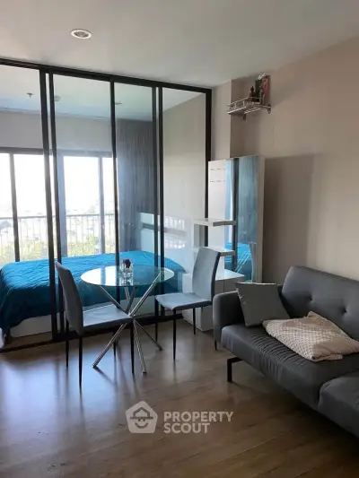 Modern studio apartment with glass partition, cozy living area, and stylish decor.