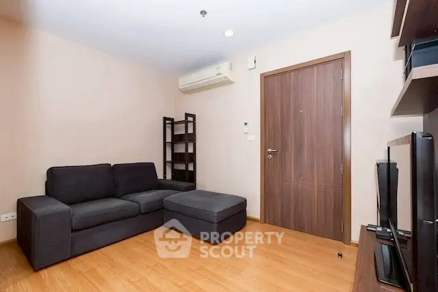 Modern living room with sleek furniture and wooden flooring, featuring a cozy black sofa and stylish shelving.