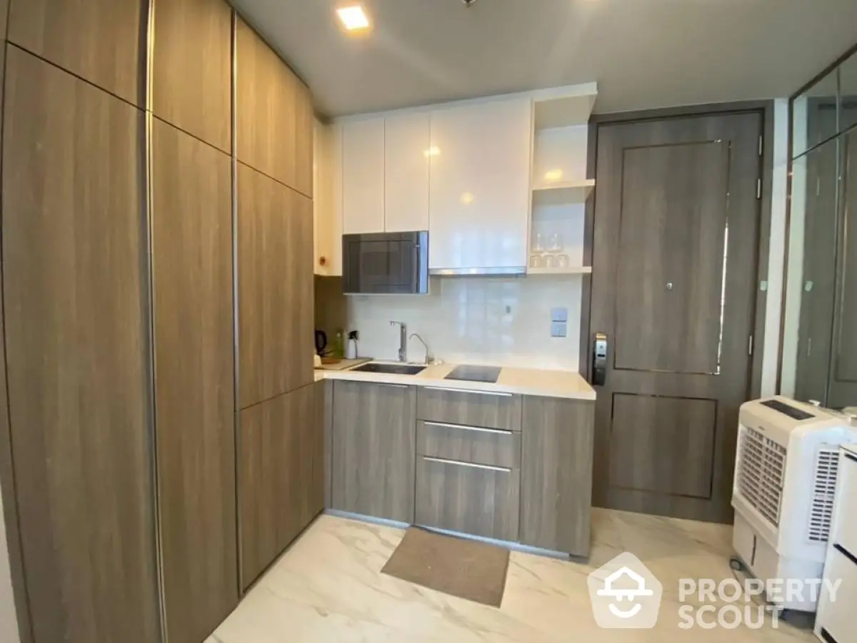 Modern compact kitchen with sleek cabinetry and integrated appliances in a stylish apartment.