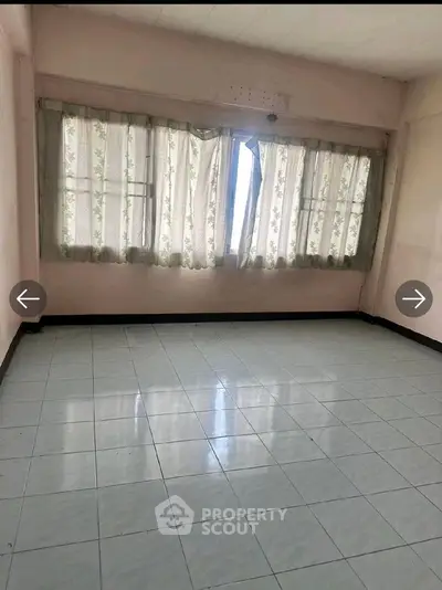 Spacious empty room with tiled floor and large windows, ideal for customization.