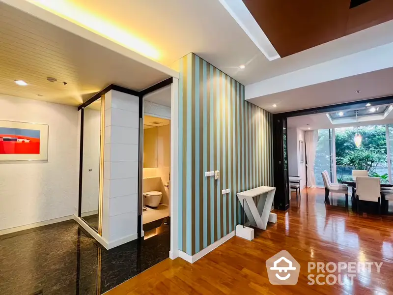 Spacious and modern living area with sleek marble flooring, ambient lighting, and a view of lush greenery through large windows, perfect for upscale urban living.