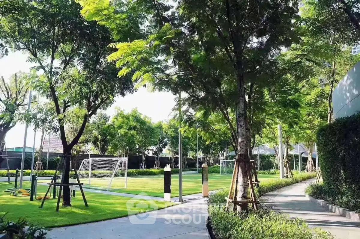 Lush garden with soccer field and pathway in residential complex