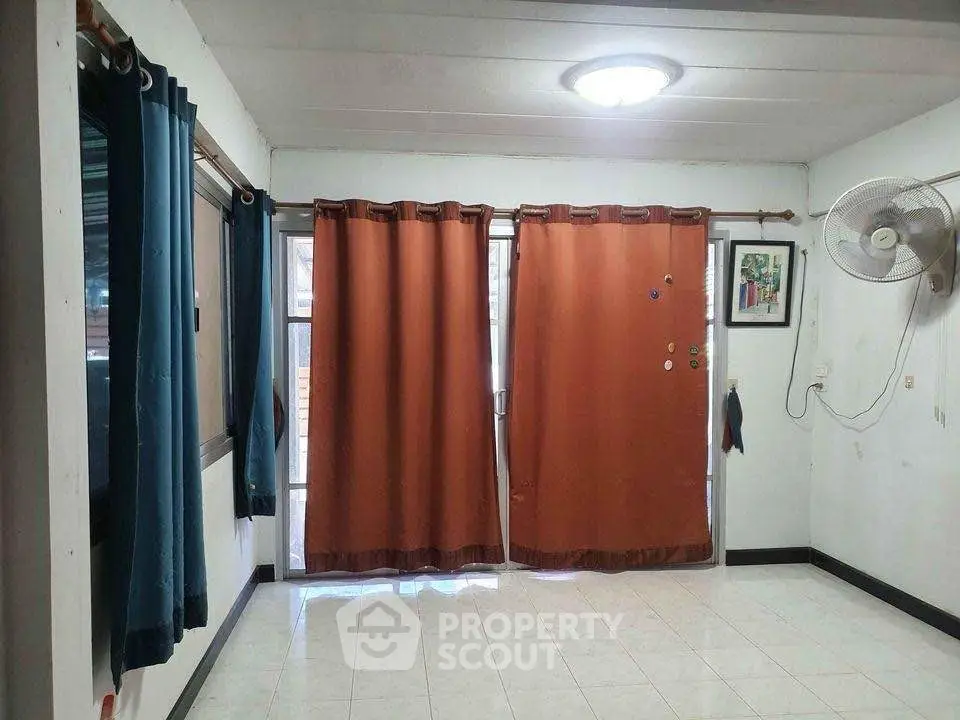 Spacious room with large windows and curtains, ideal for customization and personal touch.