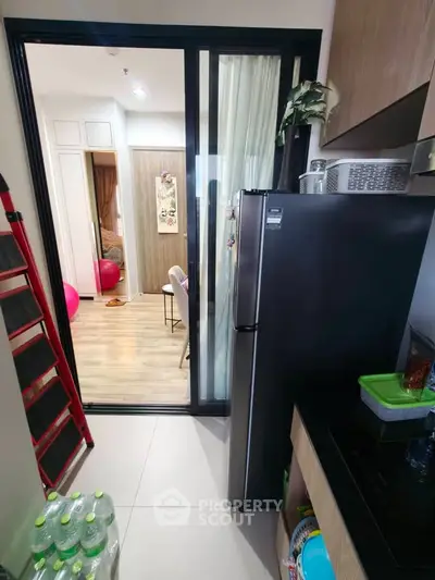Modern kitchen with sleek black fridge and open layout leading to a cozy bedroom.