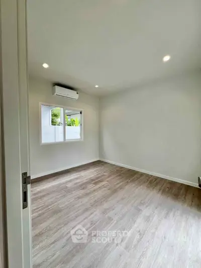 Spacious empty room with wooden flooring and air conditioning, perfect for customization.