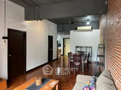 Spacious industrial-style living room with exposed brick wall and modern furnishings.