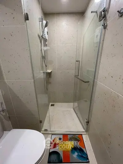Modern bathroom with glass shower enclosure and stylish floor mat