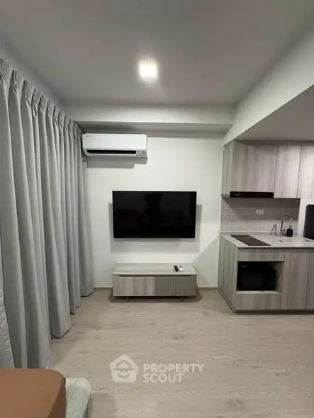 Modern living room with sleek TV setup and stylish kitchen area