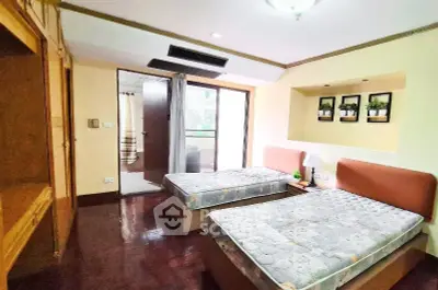 Spacious bedroom with twin beds and balcony access in modern apartment.