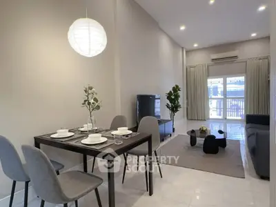 Modern living room with dining area, stylish furniture, and elegant lighting in a spacious open layout.