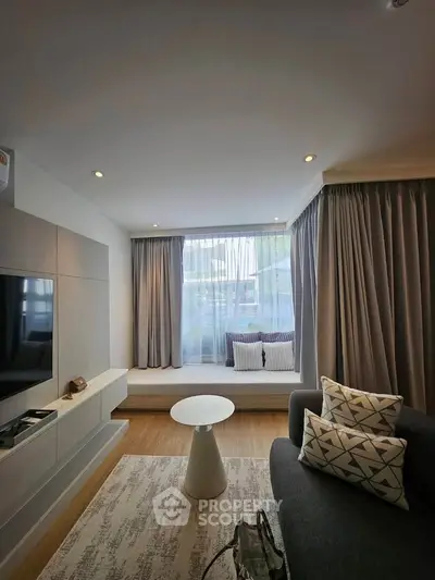 Modern living room with cozy seating and large window, perfect for relaxation and entertainment.