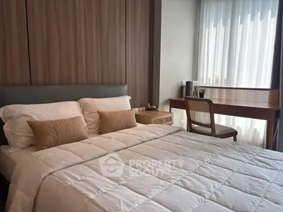Elegant bedroom with cozy bedding and stylish wooden desk by the window, perfect for relaxation and work.