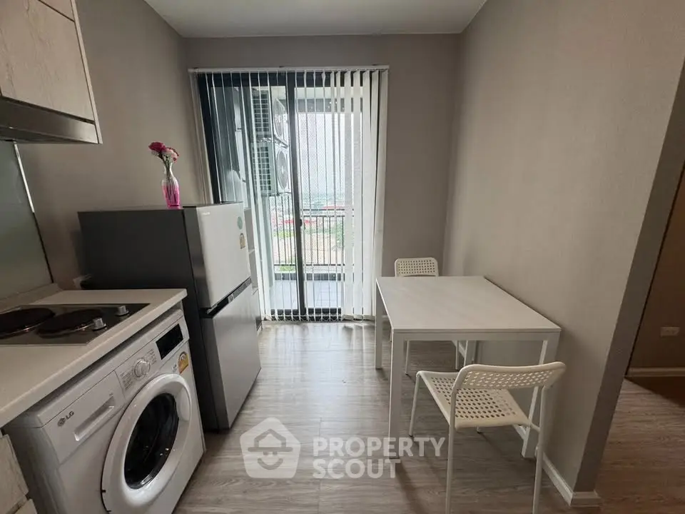 Modern kitchen with compact dining area and washing machine, featuring sleek design and natural light.