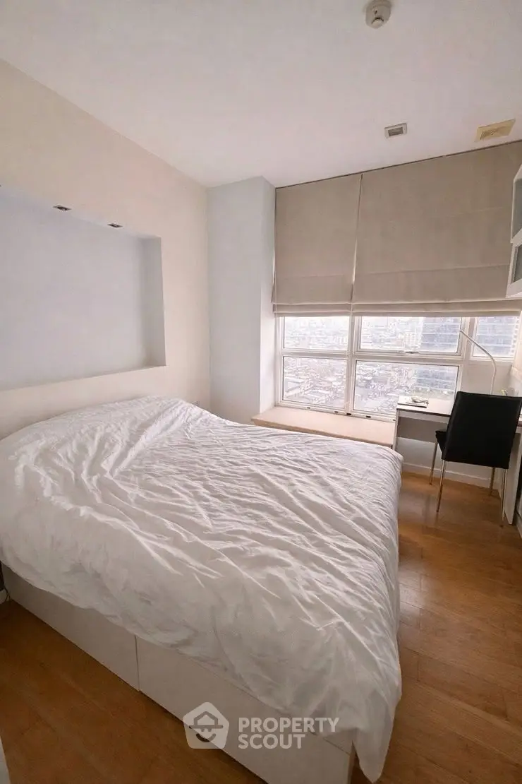 Cozy bedroom with city view, featuring a comfortable bed and a study desk by the window.