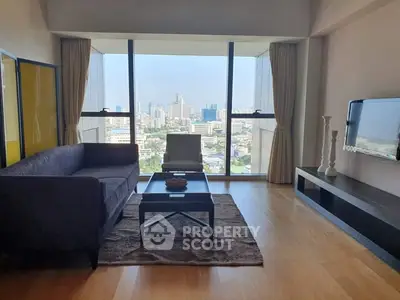 Modern living room with city view, featuring sleek furniture and large windows.