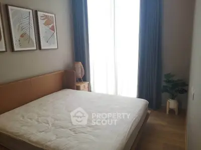 Cozy bedroom with natural light, stylish decor, and wooden flooring, perfect for relaxation.