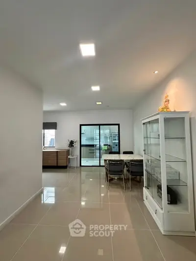 Spacious modern dining area with sleek glass cabinet and elegant lighting