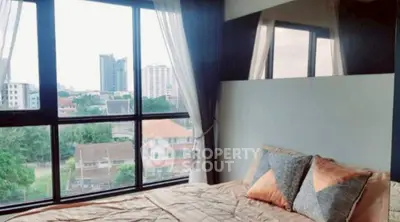 Cozy bedroom with large window offering stunning city view in modern apartment.
