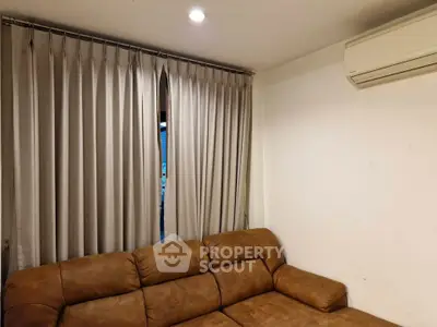 Cozy living room with brown leather sofa and air conditioning, perfect for relaxation.