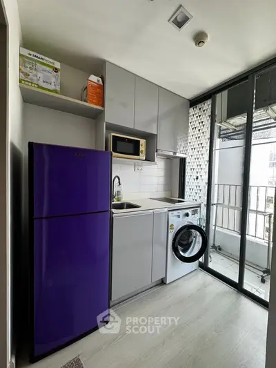 Modern compact kitchen with purple fridge and washing machine in a stylish apartment