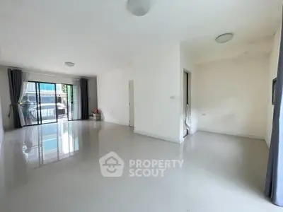 Spacious empty living room with glossy floors and large windows leading to balcony.