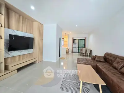 Modern living room with stylish furniture and open layout leading to dining area.