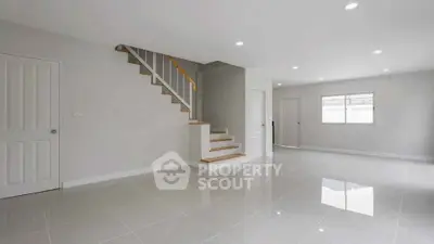 Spacious modern living room with sleek staircase and glossy tiled floors
