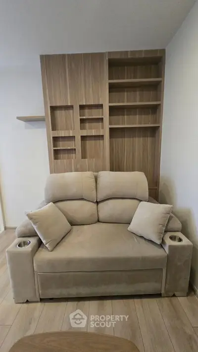 Cozy living room with plush beige sofa and modern wooden shelving unit.