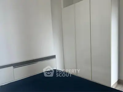 Modern minimalist bedroom with sleek white wardrobe and cozy bed.