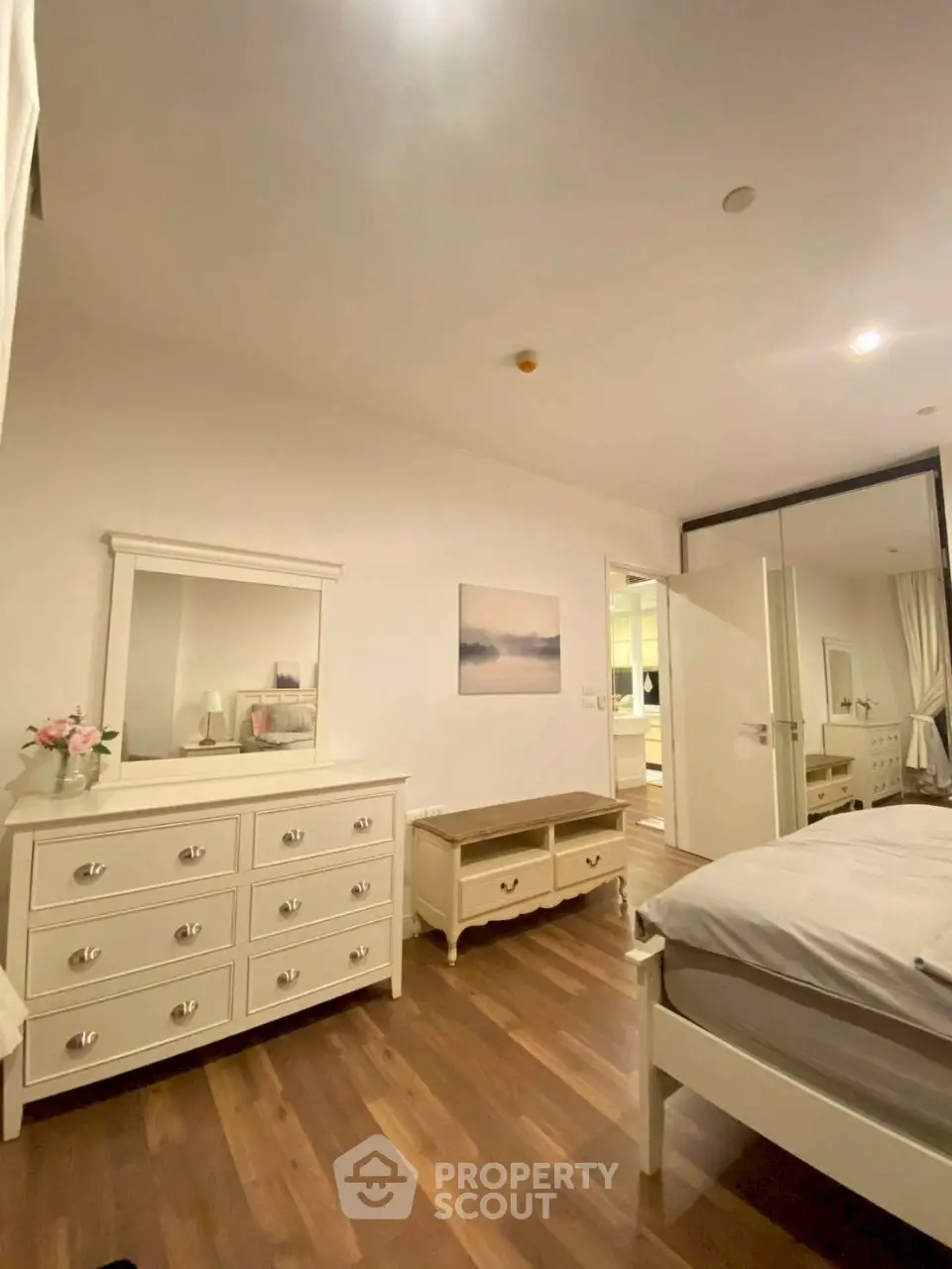 Spacious bedroom with elegant white furniture and wooden flooring